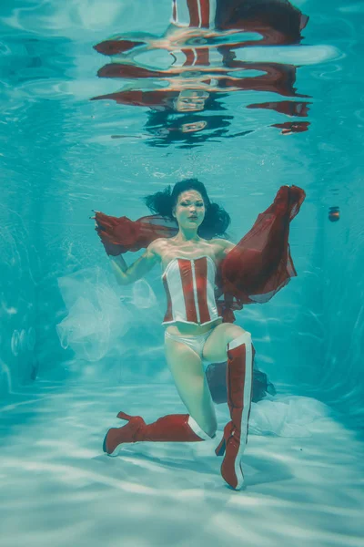 美丽性感的女孩游泳水下运动风格的红色和白色恋物癖紧身胸衣和膝盖大腿高靴子与高跟鞋 — 图库照片