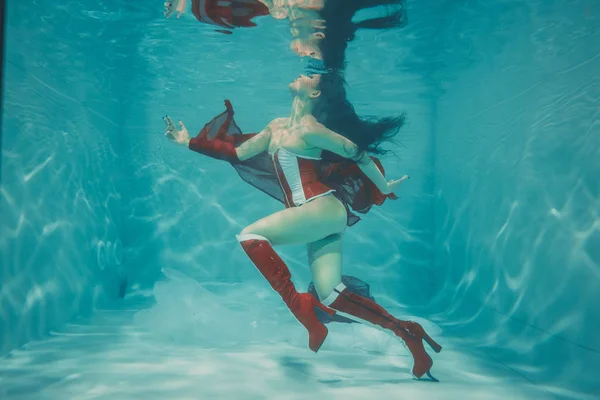 beautiful sexy girl swimming underwater in sporty style red and white fetish corset and over knee thigh high boots with heels