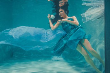 eğleniyor ve meditatively su altında bir elbise içinde yüzme sırasında kahvaltı için yatıştırıcı çay içme kız