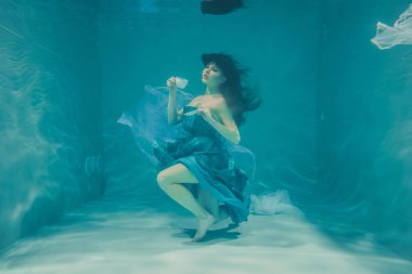 eğleniyor ve meditatively su altında bir elbise içinde yüzme sırasında kahvaltı için yatıştırıcı çay içme kız