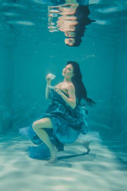 eğleniyor ve meditatively su altında bir elbise içinde yüzme sırasında kahvaltı için yatıştırıcı çay içme kız