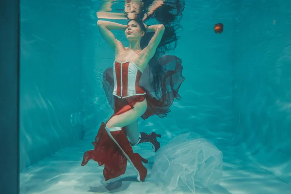 beautiful sexy girl swimming underwater in sporty style red and white fetish corset and over knee thigh high boots with heels