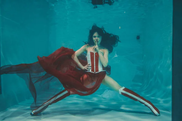 beautiful sexy girl swimming underwater in sporty style red and white fetish corset and over knee thigh high boots with heels
