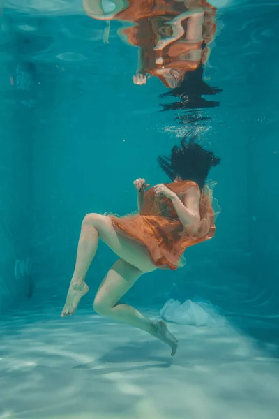 Gyönyörű Modell Lány Úszik Víz Alatt Narancssárga Ruha Élvezi Relaxációs — Stock Fotó