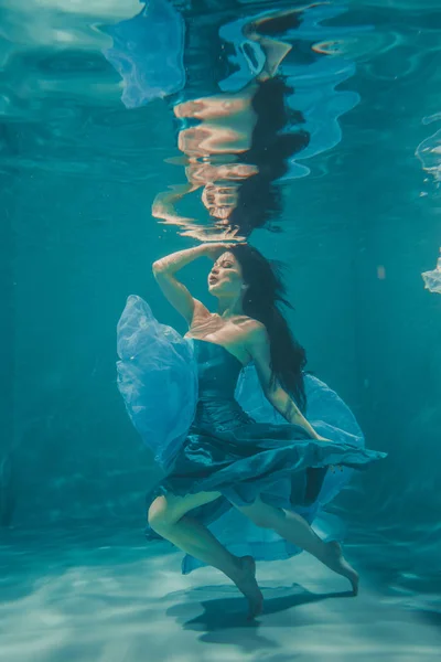 美丽的模特女孩与长黑头发游泳水下晚上蓝色礼服 享受放松和缺乏压力 — 图库照片