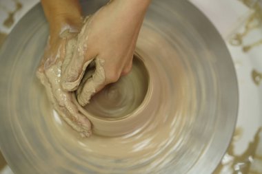 Potter's tekerlek üzerinden ham ıslak kil üzerinde kirli silah ile bir sürahi kadın yapar