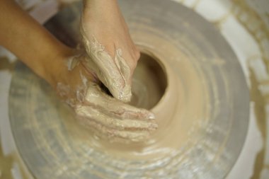 Potter's tekerlek üzerinden ham ıslak kil üzerinde kirli silah ile bir sürahi kadın yapar