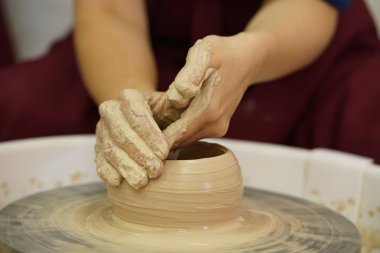 Potter's tekerlek üzerinden ham ıslak kil üzerinde kirli silah ile bir sürahi kadın yapar