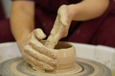 Potter's tekerlek üzerinden ham ıslak kil üzerinde kirli silah ile bir sürahi kadın yapar