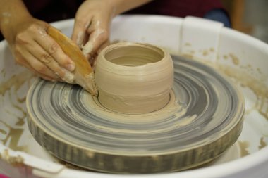 Potter's tekerlek üzerinden ham ıslak kil üzerinde kirli silah ile bir sürahi kadın yapar