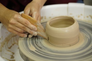 Potter's tekerlek üzerinden ham ıslak kil üzerinde kirli silah ile bir sürahi kadın yapar