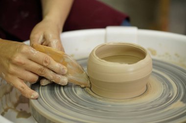 Potter's tekerlek üzerinden ham ıslak kil üzerinde kirli silah ile bir sürahi kadın yapar