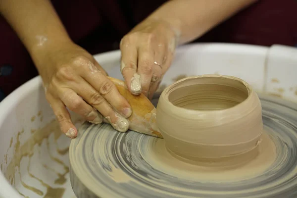 woman makes a jug with dirty arms on a Potter\'s wheel from raw wet clay
