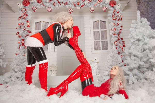 两个穿着乳胶服装的坏圣诞老人的女朋友在圣诞节在他们家的前院玩耍 — 图库照片