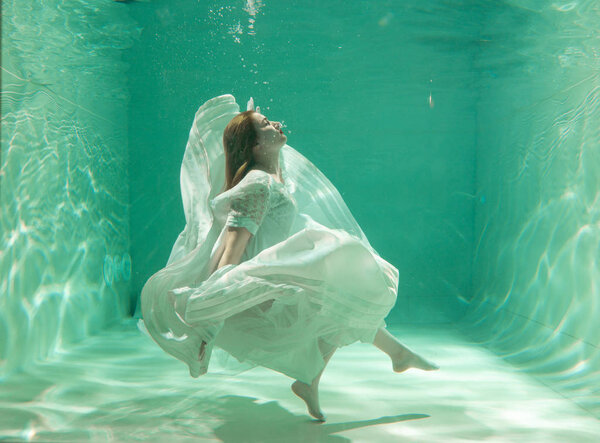 Hot Slim Caucasian Woman Posing Under water in beautiful clothes alone in the deep
