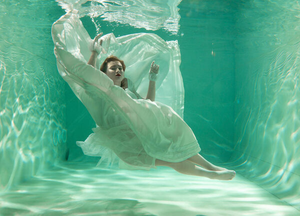 Hot Slim Caucasian Woman Posing Under water in beautiful clothes alone in the deep
