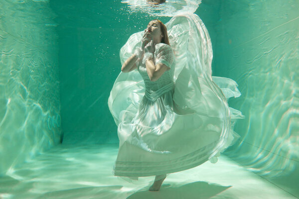 Hot Slim Caucasian Woman Posing Under water in beautiful clothes alone in the deep