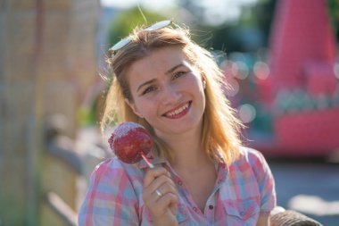 yeme ve kırmızı karamelli elma Park güneşli bir günde ısırma genç ve güzel kadın