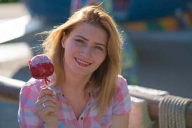 yeme ve kırmızı karamelli elma Park güneşli bir günde ısırma genç ve güzel kadın