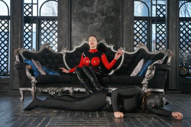 kötü güçlü metresi Fetiş Lateks catsuit giyen ve köpek kölesi deri maske ile karanlık Gotik arka plan üzerinde oynarken siyah saçlı