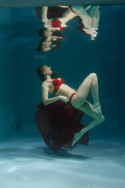 深いだけで赤のセクシーなランジェリーで水中を泳いでかなり白人の長い髪の女性 — ストック写真