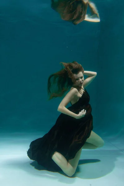 美丽的女士在长的晚礼服游泳在水下的深处独自 — 图库照片