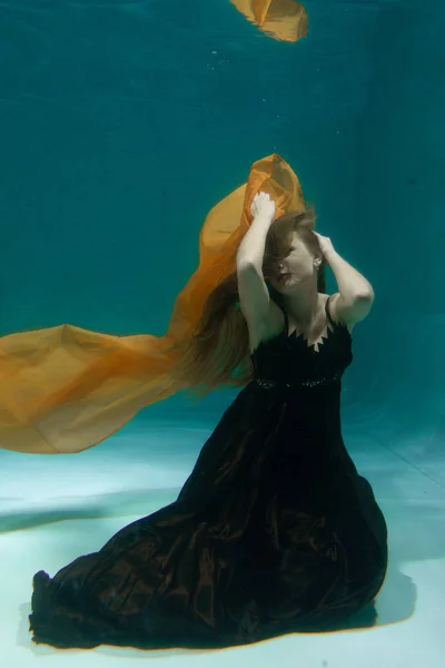 美丽的女士在长的晚礼服游泳在水下的深处独自 — 图库照片