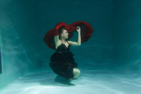 beautiful free diver woman swimming in long evening dress under water alone in the deep