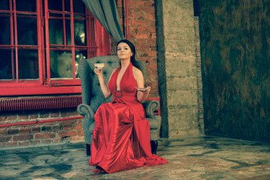 neşeli esmer beyaz kadın kırmızı uzun Abiye beyaz fincan gri bir sandalye ve içecek çay üzerinde oturan