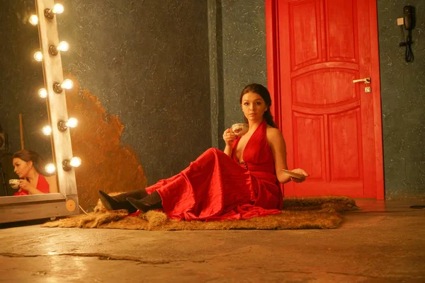 穿着红色衣服的漂亮女孩坐在皮草地毯上 喝着白色瓷杯的咖啡 — 图库照片