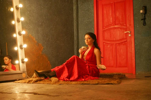 穿着红色衣服的漂亮女孩坐在皮草地毯上 喝着白色瓷杯的咖啡 — 图库照片