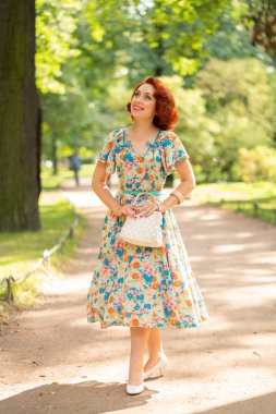 şehirde Park yaşam yaz güneşli günde zevk retro elbiseli kırmızı bob saç kesimi ile sevimli beyaz kız