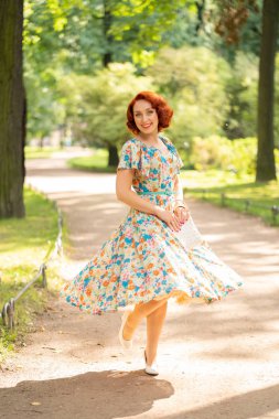 şehirde Park yaşam yaz güneşli günde zevk retro elbiseli kırmızı bob saç kesimi ile sevimli beyaz kız