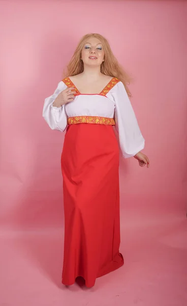 スタジオで固体のピンクの背景に赤と白の国立ロシア サンドレスで美しいぽっちゃり白人ブロンドの女の子 — ストック写真