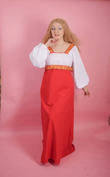 スタジオで固体のピンクの背景に赤と白の国立ロシア サンドレスで美しいぽっちゃり白人ブロンドの女の子 — ストック写真