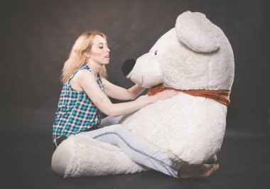 Sevimli sarışın teen kot pantolon ve ekose gömlek büyük Teddy kutup ayısının yalnız siyah arka plan üzerine sarı fularlı çalış