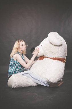 Sevimli sarışın teen kot pantolon ve ekose gömlek büyük Teddy kutup ayısının yalnız siyah arka plan üzerine sarı fularlı çalış