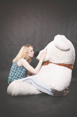 Sevimli sarışın teen kot pantolon ve ekose gömlek büyük Teddy kutup ayısının yalnız siyah arka plan üzerine sarı fularlı çalış