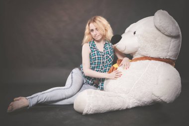 Sevimli sarışın teen kot pantolon ve ekose gömlek büyük Teddy kutup ayısının yalnız siyah arka plan üzerine sarı fularlı çalış