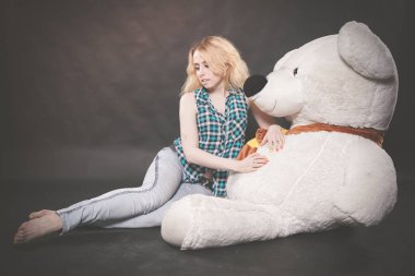 Sevimli sarışın teen kot pantolon ve ekose gömlek büyük Teddy kutup ayısının yalnız siyah arka plan üzerine sarı fularlı çalış