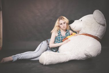 Sevimli sarışın teen kot pantolon ve ekose gömlek büyük Teddy kutup ayısının yalnız siyah arka plan üzerine sarı fularlı çalış