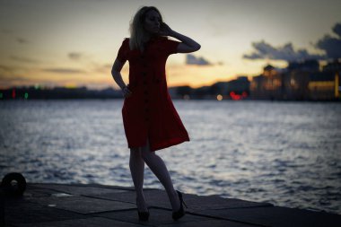 Geceleri yalnız Nehri yakınında gün batımında güzel beyaz kız yürüyor