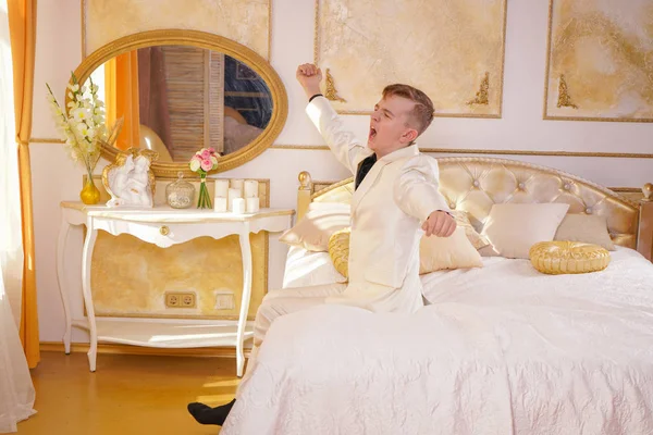 Beyaz Takım Elbise Giyen Altın Odası Yatakta Yatarken Germe Esneme — Stok fotoğraf