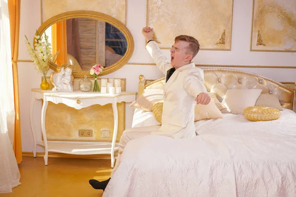 Beyaz Takım Elbise Giyen Altın Odası Yatakta Yatarken Germe Esneme — Stok fotoğraf