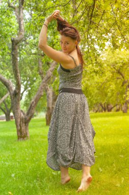 Kızıl saçlı alternatif kız güneşli elma bahçesi traş yürüyüşleri ile bir güneşli yaz gününde gülümseyen