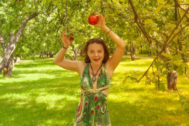 Kızıl saçlı alternatif kız güneşli elma bahçesi traş yürüyüşleri ile bir güneşli yaz gününde gülümseyen