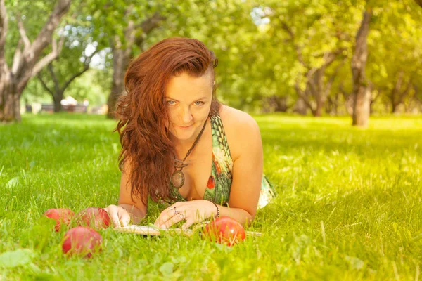 pretty smiling happy girl in green dress reading book and lying on the grass