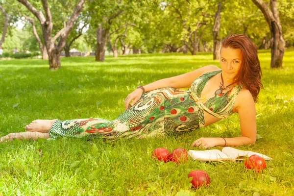 本を読むと 草の上に横になっている緑のドレスでかなり笑顔幸せな女の子 — ストック写真