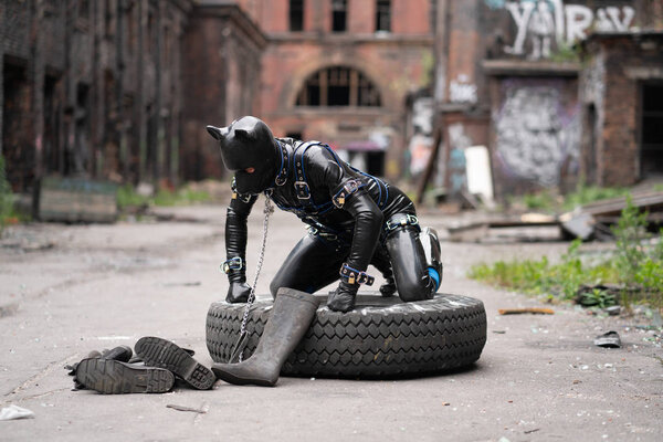 Взрослый извращенец, одетый в фетиш латексный резиновый костюм с извращенной маской
