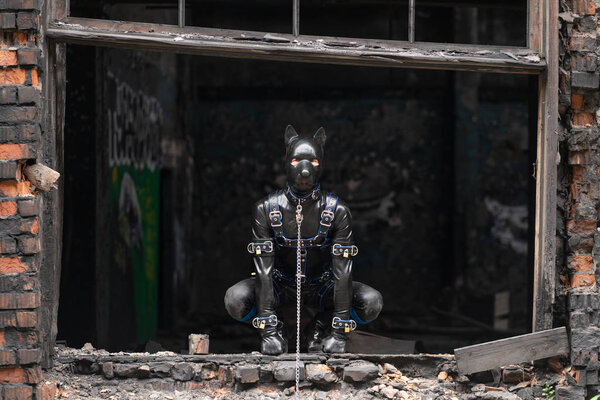 Взрослый извращенец, одетый в фетиш латексный резиновый костюм с извращенной маской
